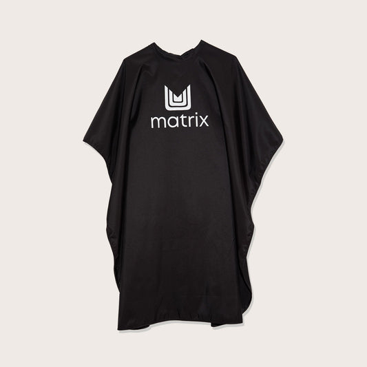 Matrix Cutting Cape — full-length matte black salon cutting cape with the Matrix logo at the chest, laid flat on a plain background