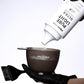 Pravana Colouring Bowl — in use, gloved hand dispensing lightener into the smoke-grey bowl with measuring scale