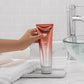 Joico YouthLock Conditioner — conditioner tube held in hand at a bathroom basin, lifestyle shot