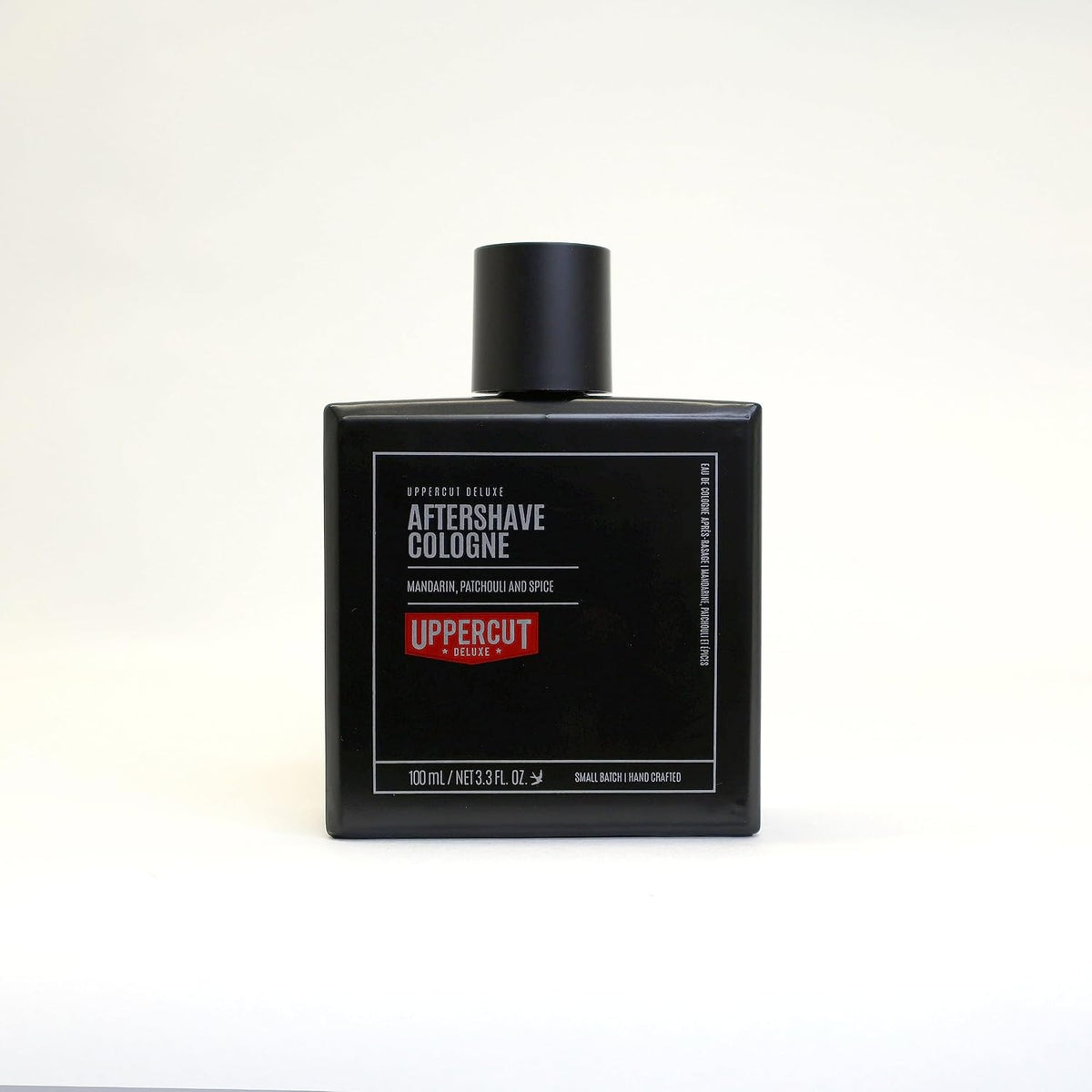 Uppercut Deluxe Aftershave Cologne — full 100 ml black glass bottle, front label, alternate studio frame