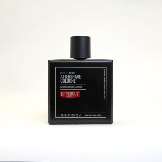 Uppercut Deluxe Aftershave Cologne — full 100 ml black glass bottle, front label, alternate studio frame