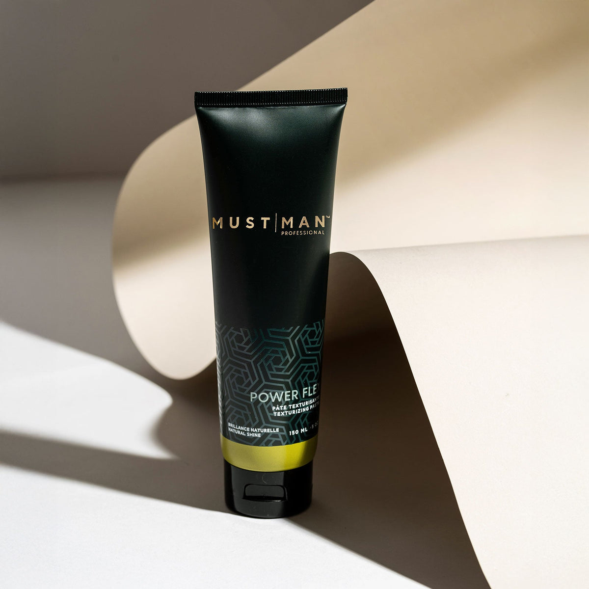 Must Man Professional Power Flex Texturizing Paste — 150 ml tube tilted on a warm neutral background