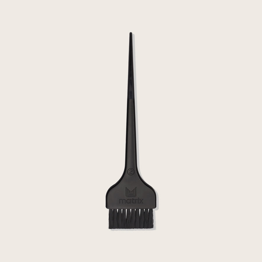 Matrix Color Brush — slim black plastic salon tint applicator brush with a long pointed sectioning tail and the Matrix mark on the handle, shown on a plain background