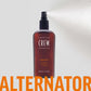American Crew Alternator Finishing Spray 100ml — 100 ml bottle releasing a fine mist against a pale backdrop