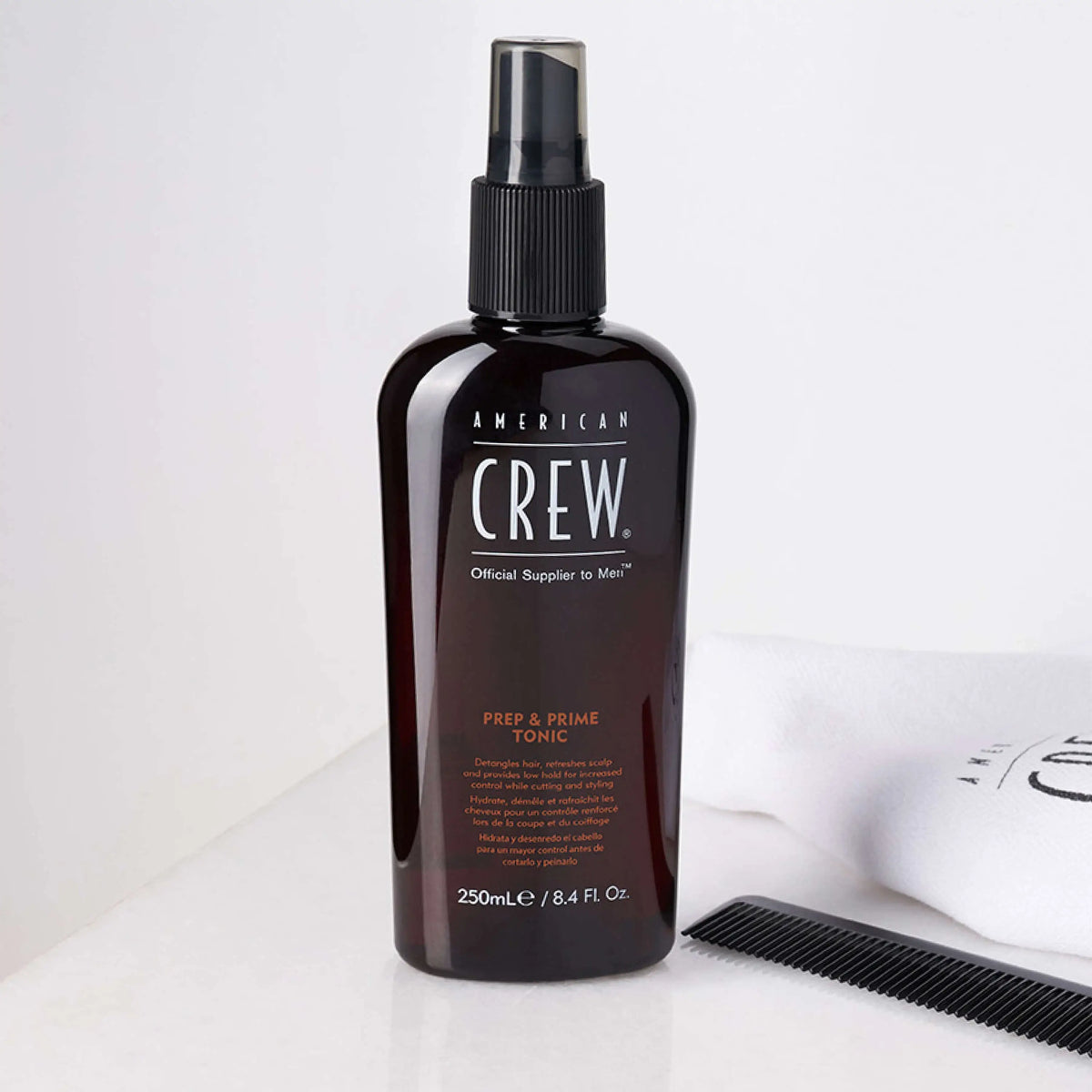 American Crew Prep & Prime Tonic — 250 ml spray bottle beside a comb on a white counter