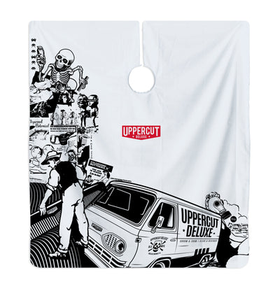 Uppercut Deluxe Barber Cape Collage — full cape laid flat, black-and-white collage artwork with the Uppercut Deluxe van and red badge, plain white background
