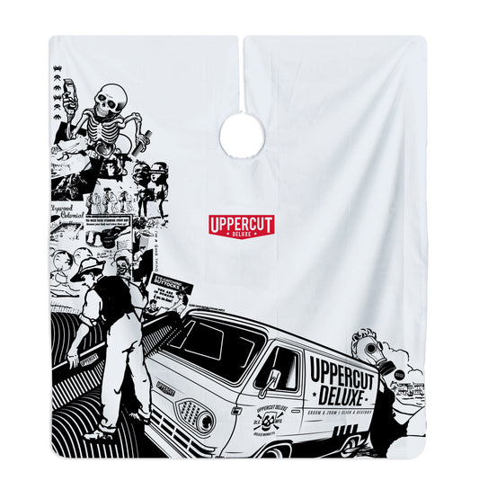 Uppercut Deluxe Barber Cape Collage — full cape laid flat, black-and-white collage artwork with the Uppercut Deluxe van and red badge, plain white background