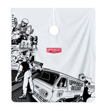 Uppercut Deluxe Barber Cape Collage — full cape laid flat, black-and-white collage artwork with the Uppercut Deluxe van and red badge, plain white background