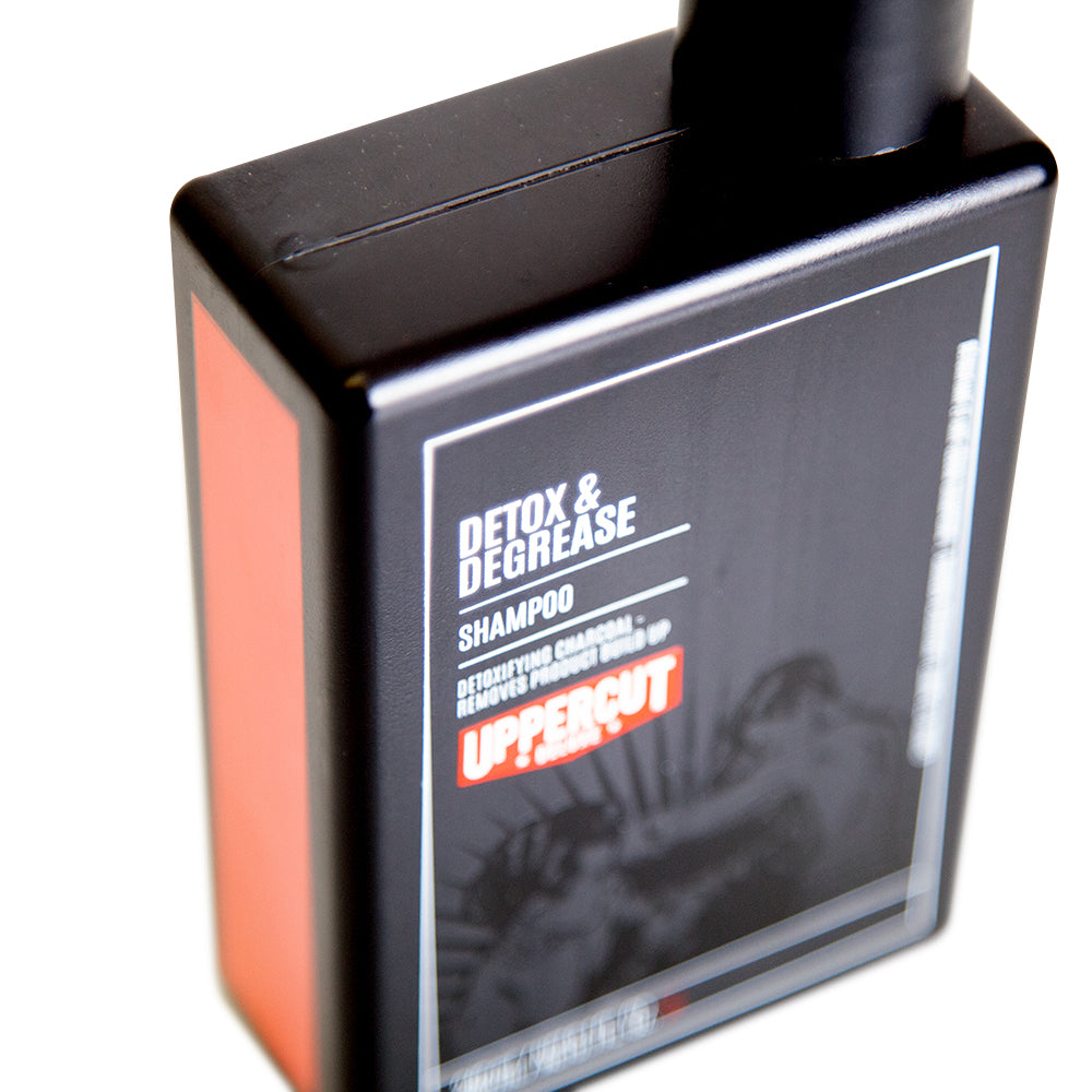 Uppercut Deluxe Detox and Degrease Shampoo 240 ml — black 240 ml shampoo bottle angled, orange label band in close-up