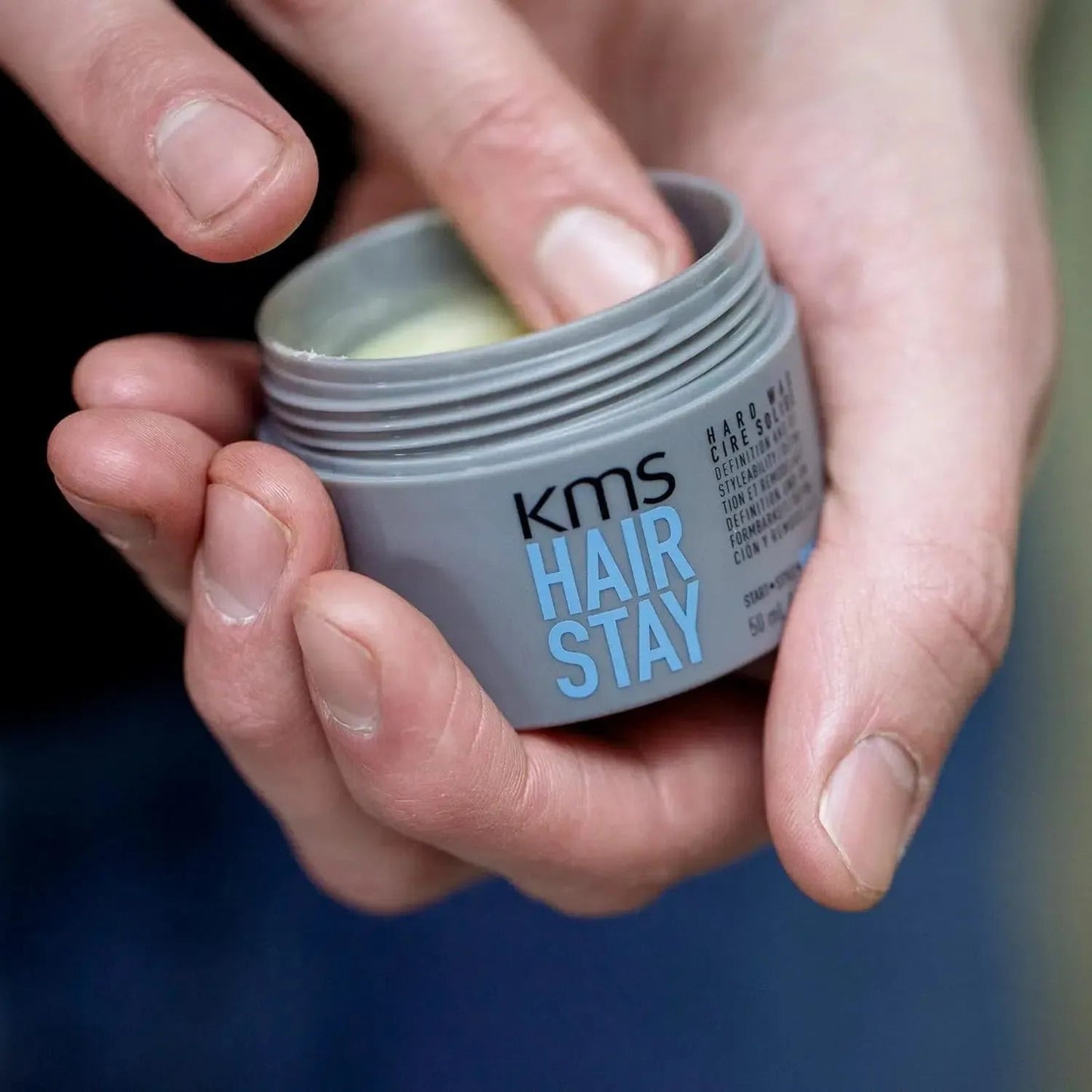 KMS HairStay Hard Wax — open 50 mL jar held in one hand, showing the dry matte wax texture