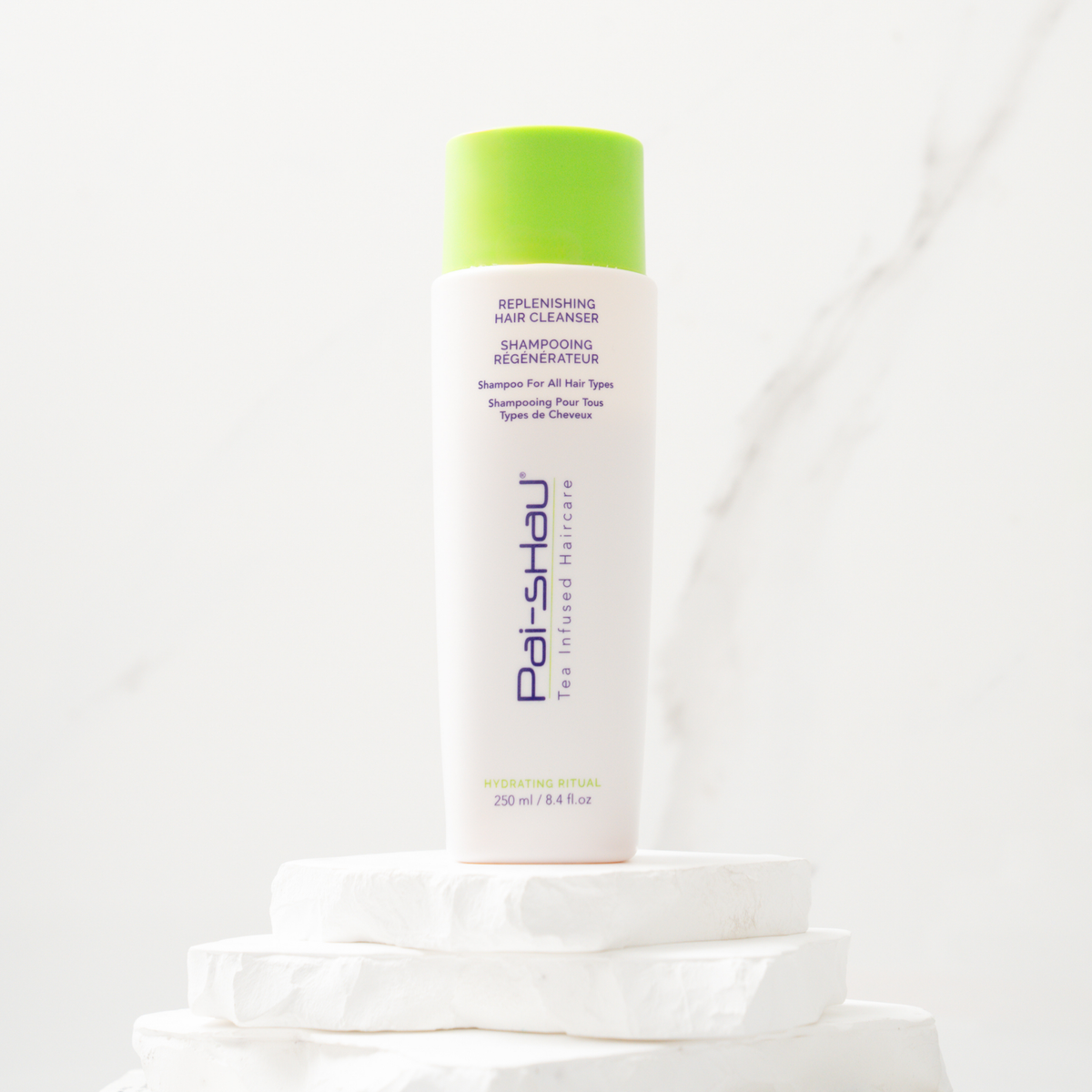 Pai-Shau Replenishing Hair Cleanser 250 ml on a marble plinth