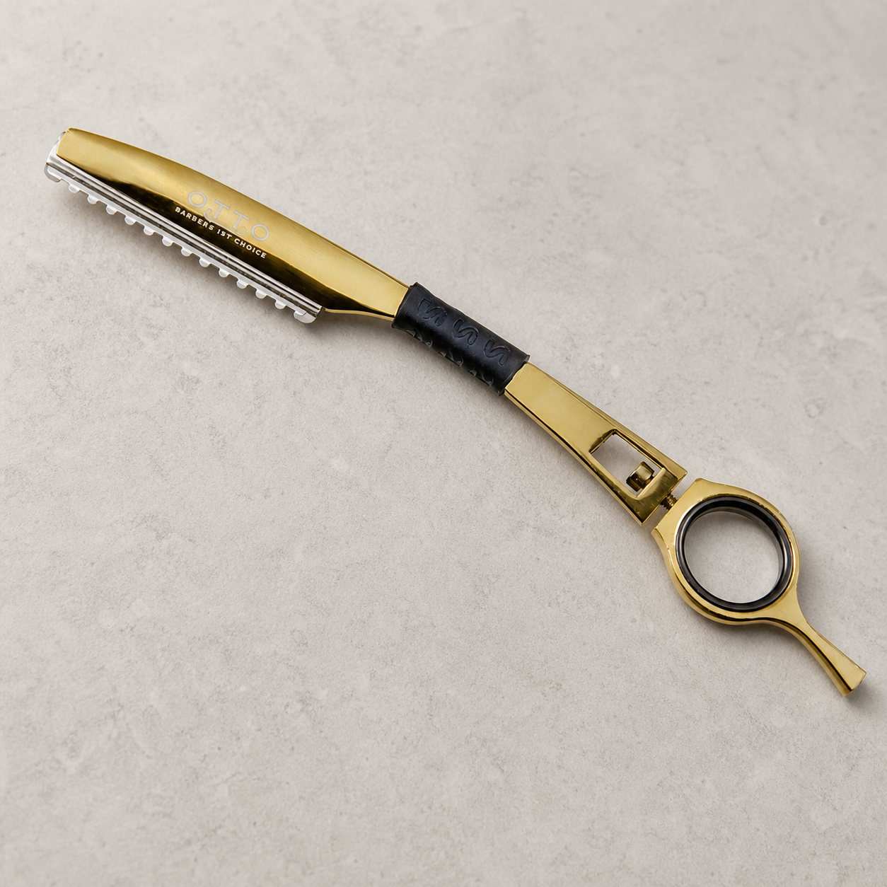 Otto gold guarded haircutting razor on a light stone salon surface
