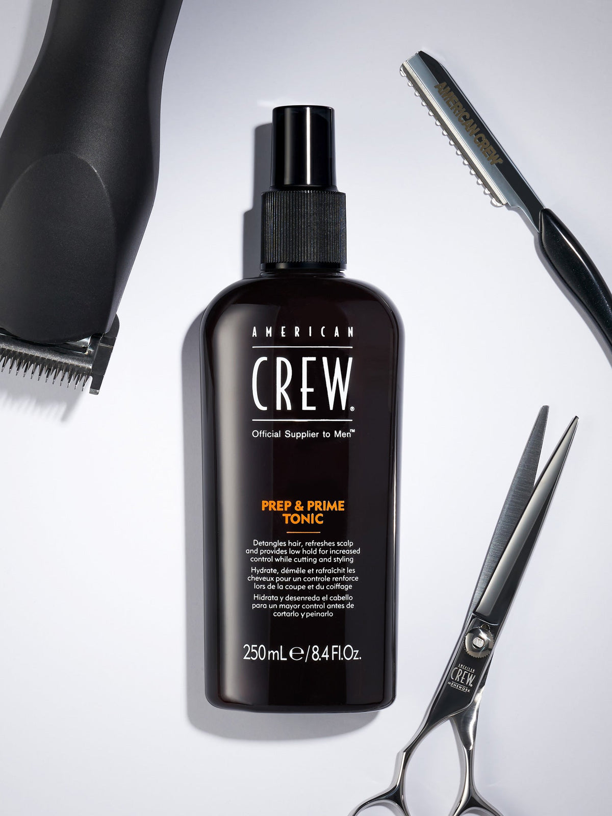 American Crew Prep & Prime Tonic — 250 ml bottle with clippers, shears and razor on a barber counter