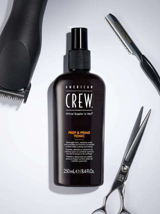 American Crew Prep & Prime Tonic — 250 ml bottle with clippers, shears and razor on a barber counter