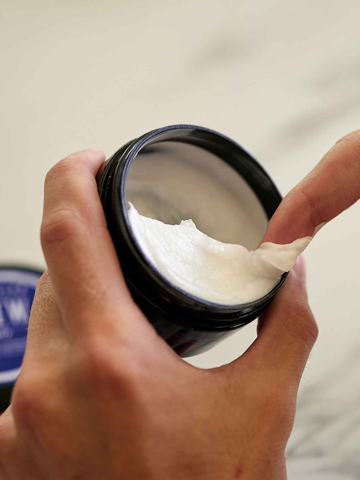 American Crew Whip Lightweight Styling Cream — hand scooping the whipped formula out of the open tub